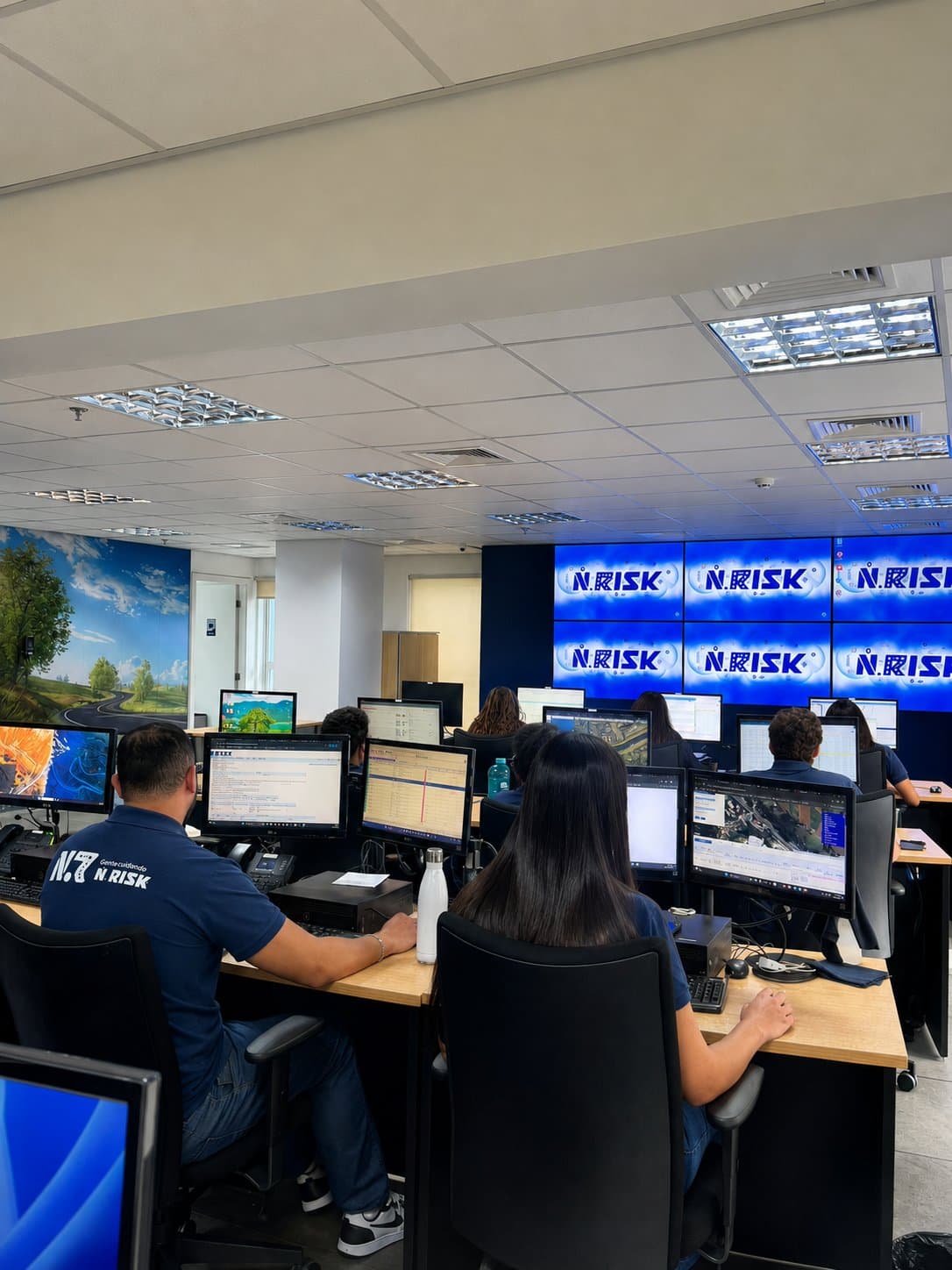 Equipe da N.RISK atuando na central de monitoramento, com telas exibindo a marca N.RISK